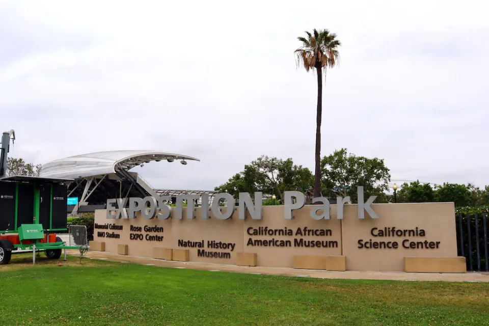Expositoin park enrtance sign in Los Angeles, California with tall palm tree in background.